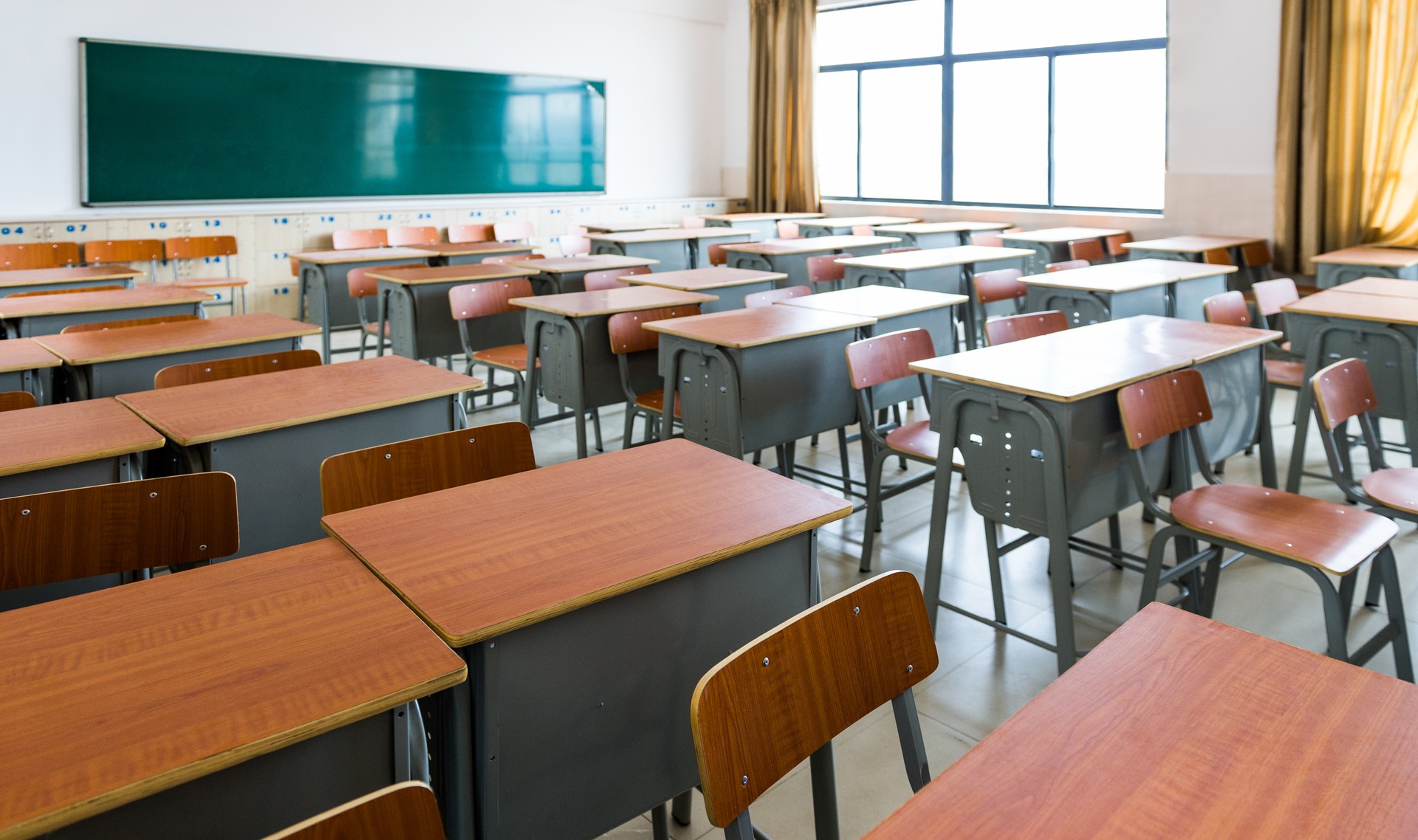 Empty classroom with desks, chairs and chalkboard